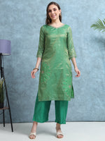 Load image into Gallery viewer, Woman wearing a green kurta with palazzo pants against a textured blue wall.
