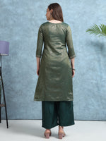 Load image into Gallery viewer, Woman wearing a green kurta with palazzo pants against a blue wall.