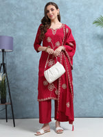 Load image into Gallery viewer, Woman wearing a red embroidered outfit with a white bag against a blue wall.