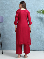 Load image into Gallery viewer, Woman wearing a red kurta with palazzo pants against a blue textured wall.