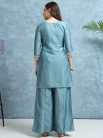 Load image into Gallery viewer, Woman wearing a light blue kurta with palazzo pants against a blue textured wall.