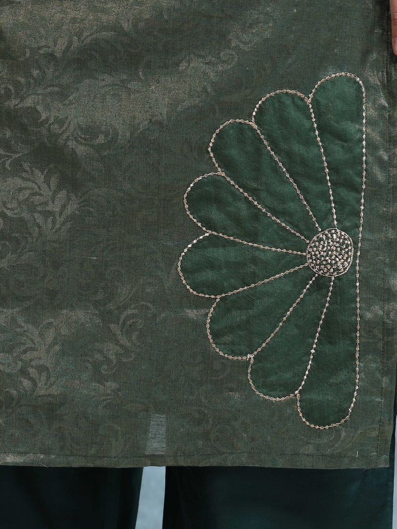Green fabric with a floral embroidery design on a dark background