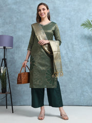 Woman wearing a green kurta with a matching dupatta, holding a brown handbag against a light blue background.