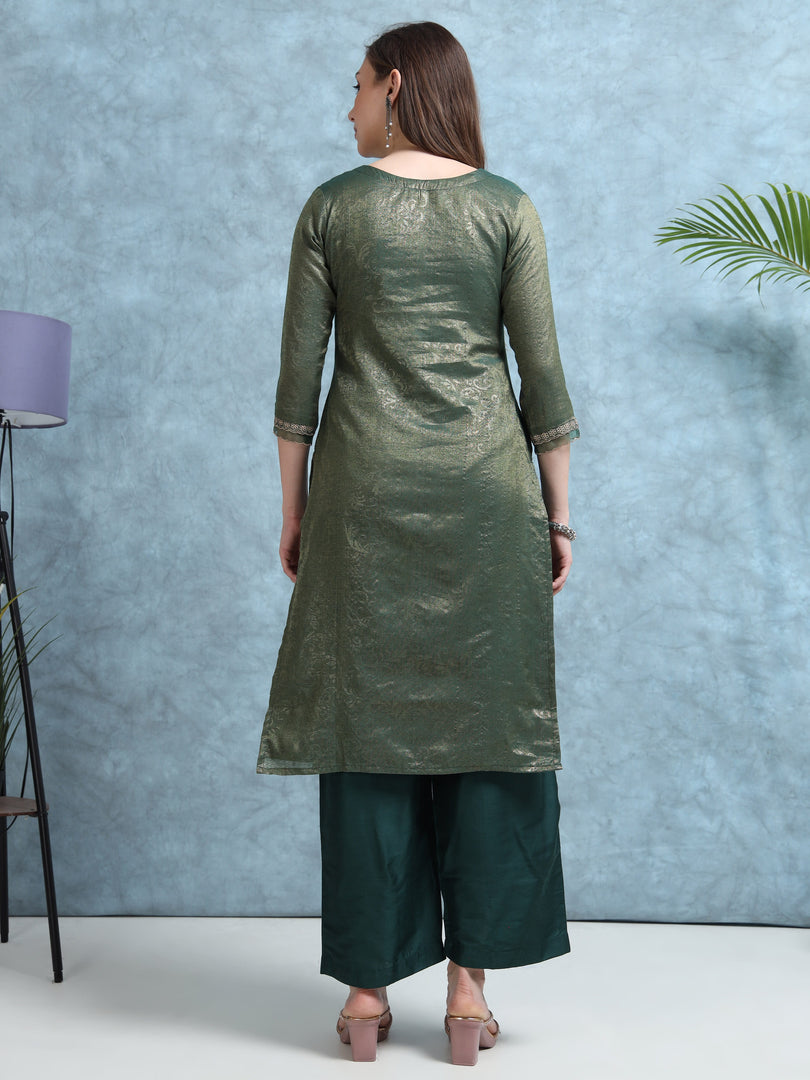 Woman wearing a green kurta with palazzo pants against a blue wall.