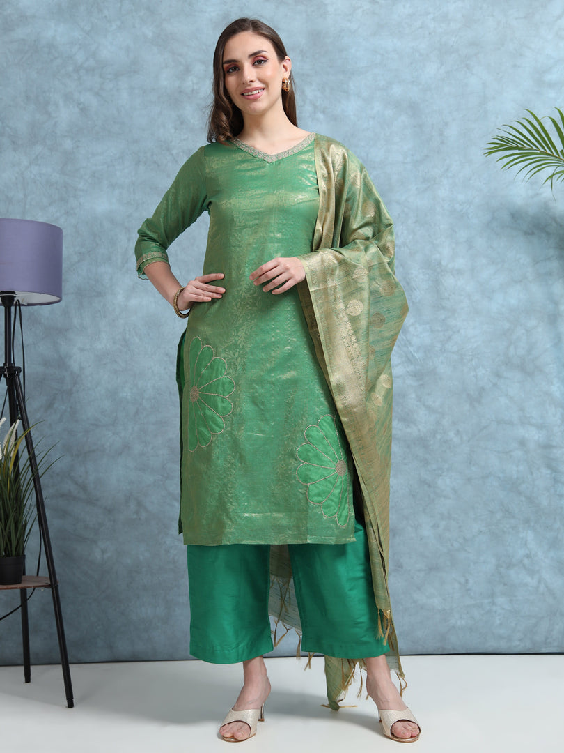 Woman wearing a green traditional outfit with a matching dupatta against a light blue background