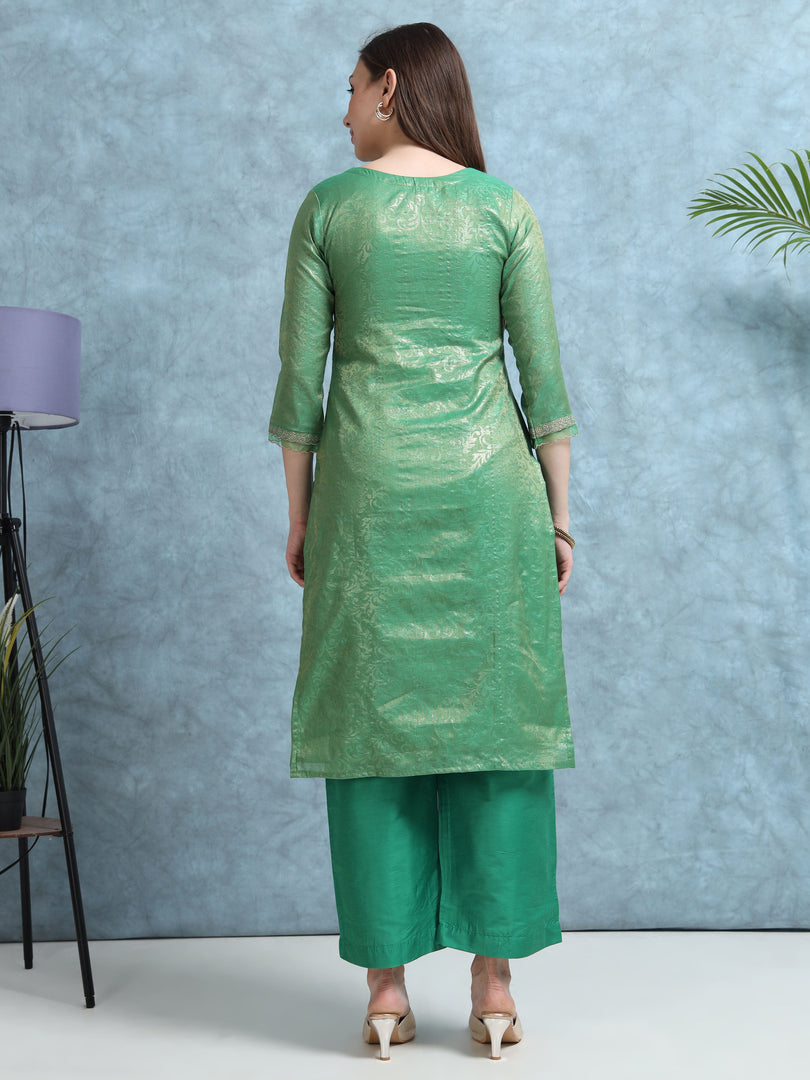 Woman wearing a green kurta with palazzo pants against a blue wall.