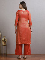 Load image into Gallery viewer, Woman wearing an orange kurta with palazzo pants standing against a gray wall.