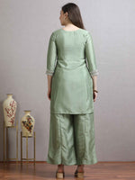 Load image into Gallery viewer, Woman wearing a light green traditional outfit standing in front of decorative vases.