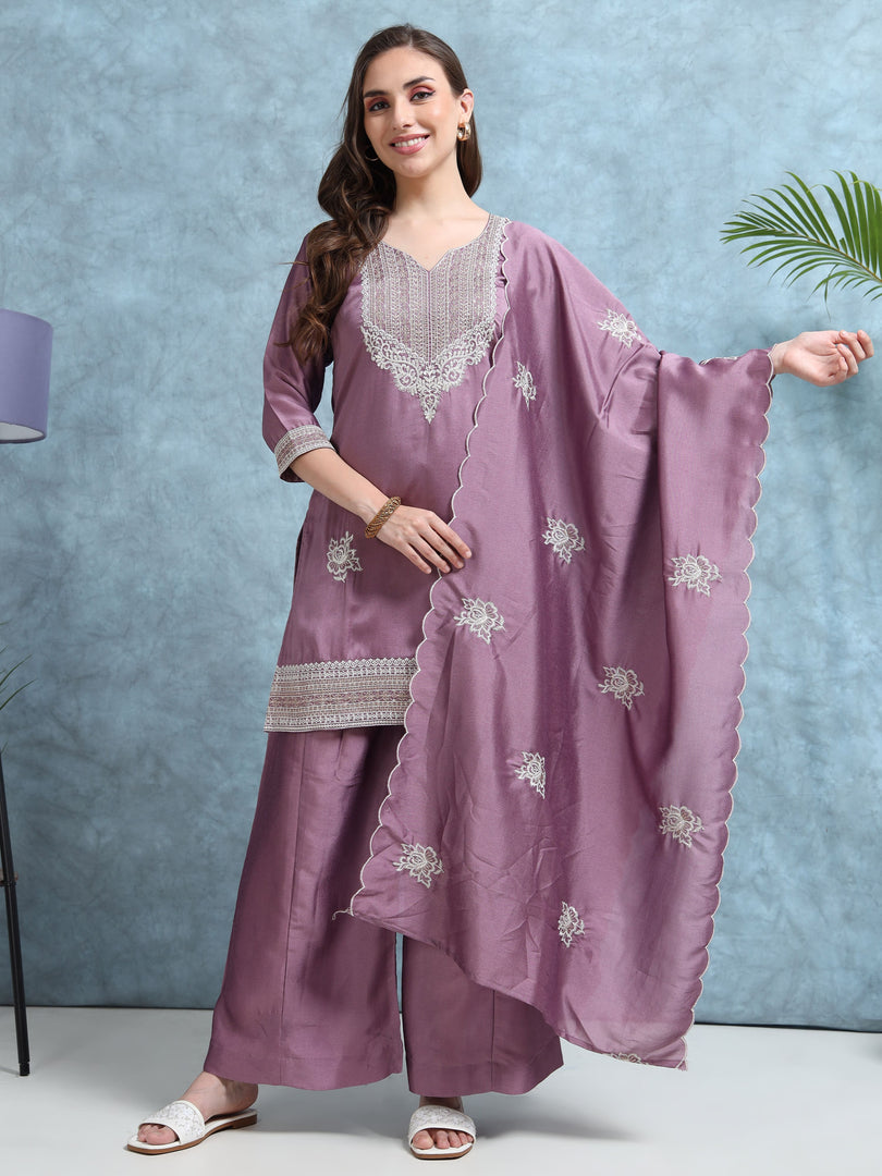 Woman wearing a mauve traditional outfit with silver embroidery against a light blue background