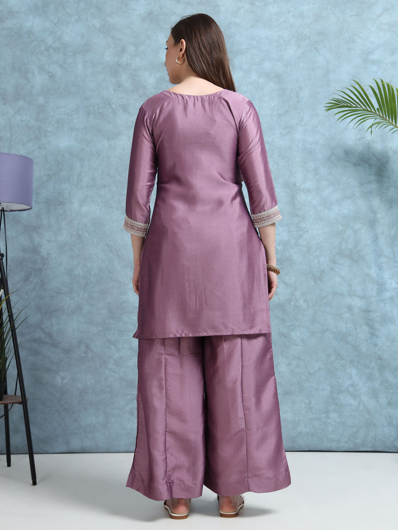 Woman wearing a mauve traditional outfit against a light blue wall.