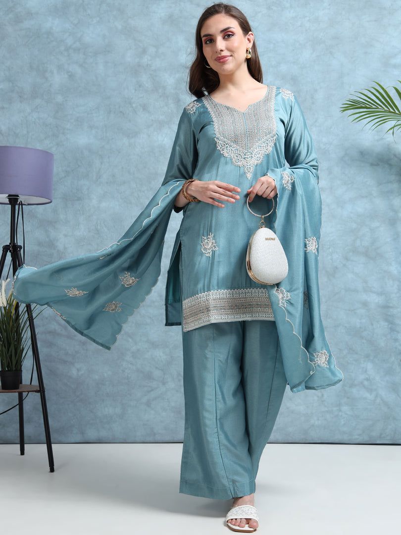 Woman wearing a light blue traditional outfit with white embroidery against a light blue background